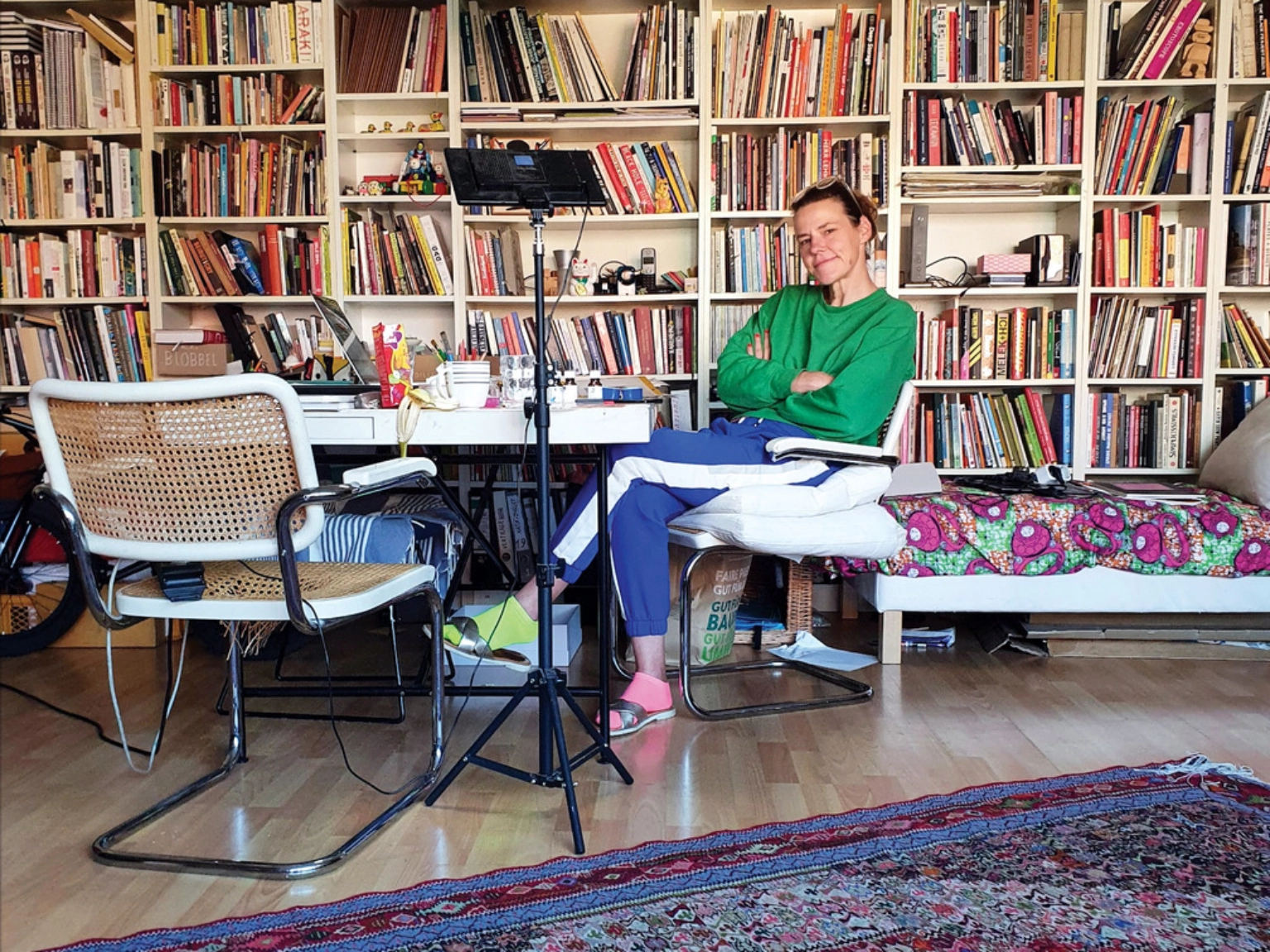 Foto mit der Comic-Künstlerin Katia Fouquet. Sie sitzt auf einem Stuhl vor einem Tisch, im Hintergrund ist eine großen Bücherwand zu sehen.