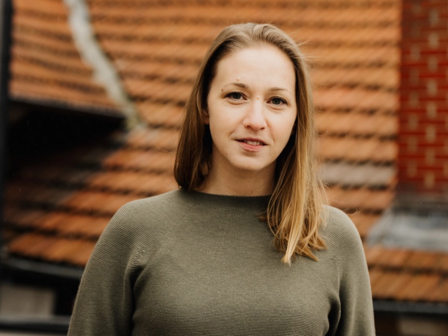 Porträt von Anna-Lena Markus, stehend auf einer Dachterrasse. 